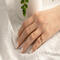 Hand wearing 14K yellow gold birthstone stackable rings with 2mm round stones sizes 4-10 on a white fabric with green plant in background  
